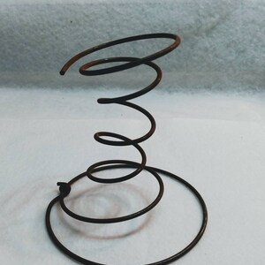 May include: A rusty metal spring coil, used as a bed frame support, with a circular base.