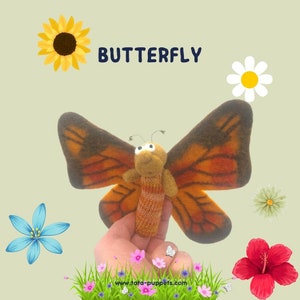 Peut inclure: Une marionnette de doigt en feutre représentant un papillon aux ailes orange et brunes. Le papillon a une tête brune avec des yeux globuleux et un corps orange rayé. La marionnette est tenue contre un fond vert avec des fleurs.