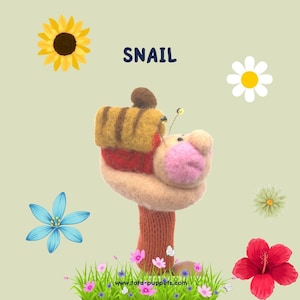 Peut inclure: Marionnette en forme d'escargot faite à la main, avec un corps beige, un visage rose et une coquille rayée jaune et marron. Le mot "SNAIL" est au-dessus de la marionnette. Le fond présente des fleurs et de l'herbe.