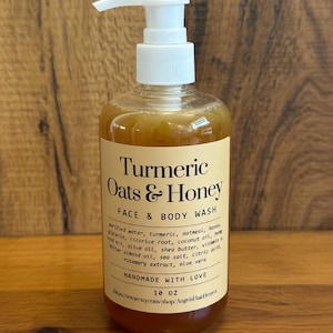 May include: A clear plastic bottle of face and body wash with a white pump dispenser. The label reads "Turmeric Oats & Honey" and lists ingredients. The bottle contains 296 ml of product.