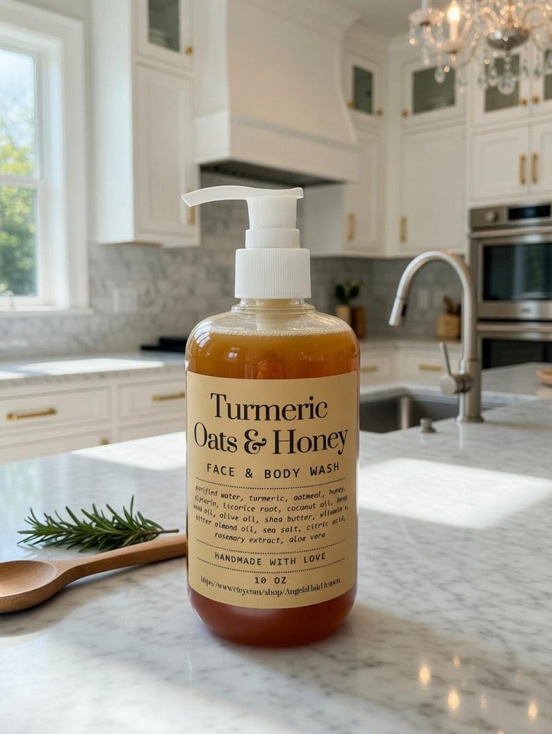 May include: A clear bottle of Turmeric Oats & Honey Face & Body Wash with a white pump dispenser. The label includes the product name and ingredients. The bottle is 295 ml. A wooden spoon and rosemary sprig are next to the bottle.