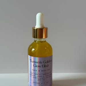 Puede incluir: Una botella de vidrio transparente llena de l&iacute;quido amarillo, con un cuentagotas dorado. La etiqueta dice "Turmeric Golden Glow Elixir FACE & BODY OIL" y enumera los ingredientes. Dice "HANDMADE WITH LOVE" y el volumen es de 60 ml.