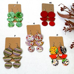 May include: Five pairs of earrings with different patterns and colors. The earrings are made of wood and have a geometric design. The earrings are displayed on a white background.