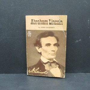May include: A vintage book titled "Abraham Lincoln" by James Daugherty. The cover features a black and white portrait of Abraham Lincoln with a signature below.