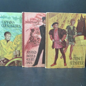 May include: Three vintage hardcover books with colorful illustrations on the covers. The titles are "Captains Courageous", "Around the World in Eighty Days", and "The Prince and the Pauper".