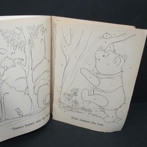 May include: A black and white colouring book page featuring Winnie the Pooh climbing a tree. The page has numbers on it for a connect-the-dots activity. The text on the page reads "Pooh climbed the tree."