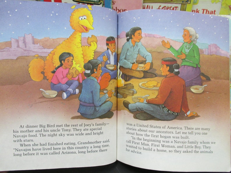 May include: A children's book illustration depicting a yellow Big Bird character with a group of people sitting around a campfire. The text reads, "At dinner Big Bird met the rest of Joey's family - his mother and his uncle Tony. They ate special Navajo food. The night sky was wide and bright with stars. When she had finished eating, Grandmother said, "Navajos have lived here in this country a long time, long before it was called Arizona, long before there was a United States of America. There are many stories about our ancestors. Let me tell you one about how the first hogan was built. "In the beginning was a Navajo family whom we call First Man, First Woman, and Little Boy. They wanted to build a home, so they asked the animals for advice."