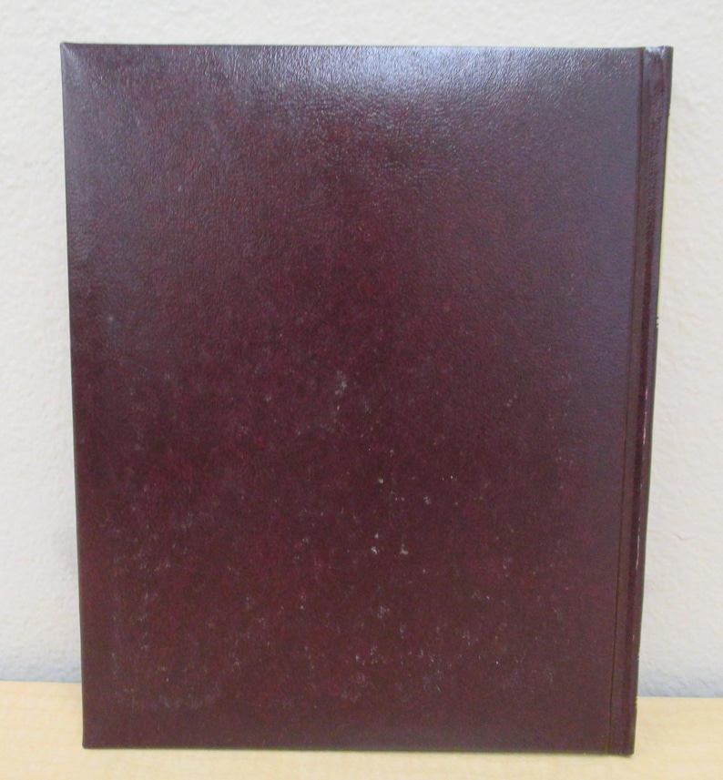 Puede incluir: Un libro de tapa dura de color burdeos oscuro con una cubierta lisa y texturizada.