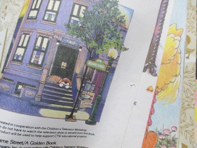 May include: An illustration of a purple building with a brown door and a sign that reads "Sesame Street". There is a tree in front of the building and a sign that says "Do Not Disturb".