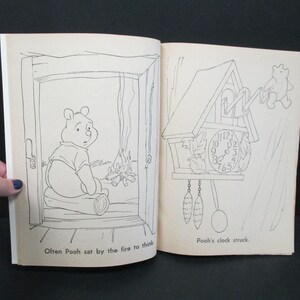 May include: A black and white illustration of Winnie the Pooh sitting by a fire. The text "Often Pooh sat by the fire to think" is below the image. On the right side of the page is a black and white illustration of a cuckoo clock with the text "Pooh's clock struck." below the image.
