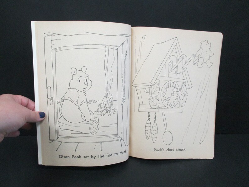May include: A black and white illustration of Winnie the Pooh sitting by a fire. The text "Often Pooh sat by the fire to think" is below the image. On the right side of the page is a black and white illustration of a cuckoo clock with the text "Pooh's clock struck." below the image.