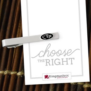 May include: A silver-toned tie bar with a black and white oval emblem featuring the letters "CTR". The tie bar is displayed on a white card with the words "choose the right" in script and the Ringmasters logo.