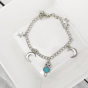 May include: Silver charm bracelet with a turquoise owl charm, two crescent moon charms, and three star charms.
