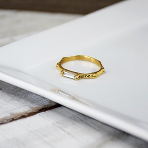 May include: Gold ring with a clear rectangular stone and the word "CTR" engraved on the band.