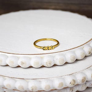 May include: A gold ring with the letters "CTR" spelled out on it.