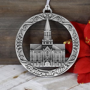 May include: Silver ornament featuring a detailed cutout of a church building with the text "Taylorsville Utah".