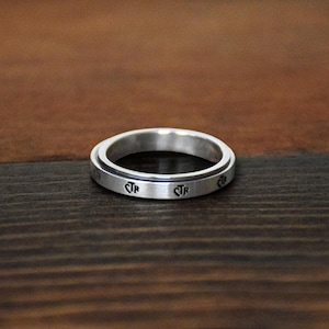 May include: A silver spinning ring with the letters "CTR" engraved on the band.