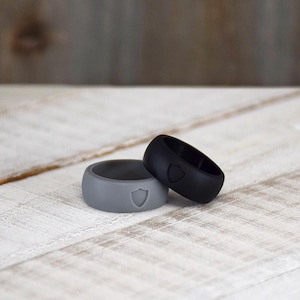 May include: Two silicone rings, one black and one gray, with a shield logo on each.