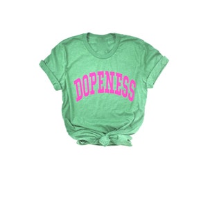 May include: A green t-shirt with the word "DOPENESS" printed in pink letters.
