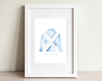 Pode incluir: Uma ilustração em aquarela de sedas de jóquei azul claro com um design em X branco. O texto "LEVI RUSSELL" é impresso abaixo das sedas.