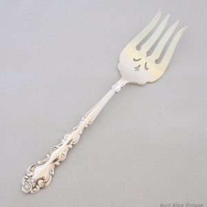 May include: A silver fork with an ornate handle and a pierced design on the tines. The fork is in good condition and has a polished finish.
