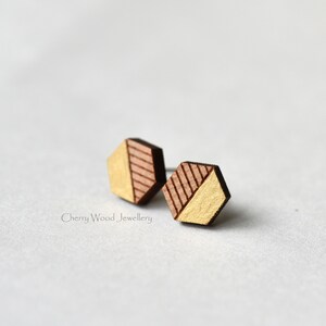 May include: A pair of geometric wooden earrings with a gold and brown color scheme. The earrings are hexagonal in shape and have a diagonal line design.