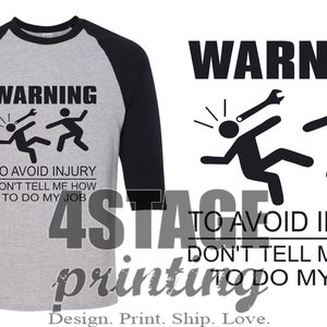 May include: A black and gray baseball style t-shirt with a black and white graphic of two stick figures. The text on the shirt reads "WARNING TO AVOID INJURY DON'T TELL ME HOW TO DO MY JOB".
