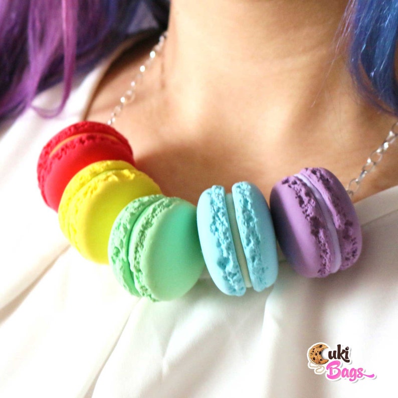 Pode incluir: Um colar de macarons arco-&iacute;ris com macarons vermelhos, amarelos, verdes, azuis e roxos. Os macarons s&atilde;o feitos de argila polim&eacute;rica e s&atilde;o enfiados em uma corrente prateada.