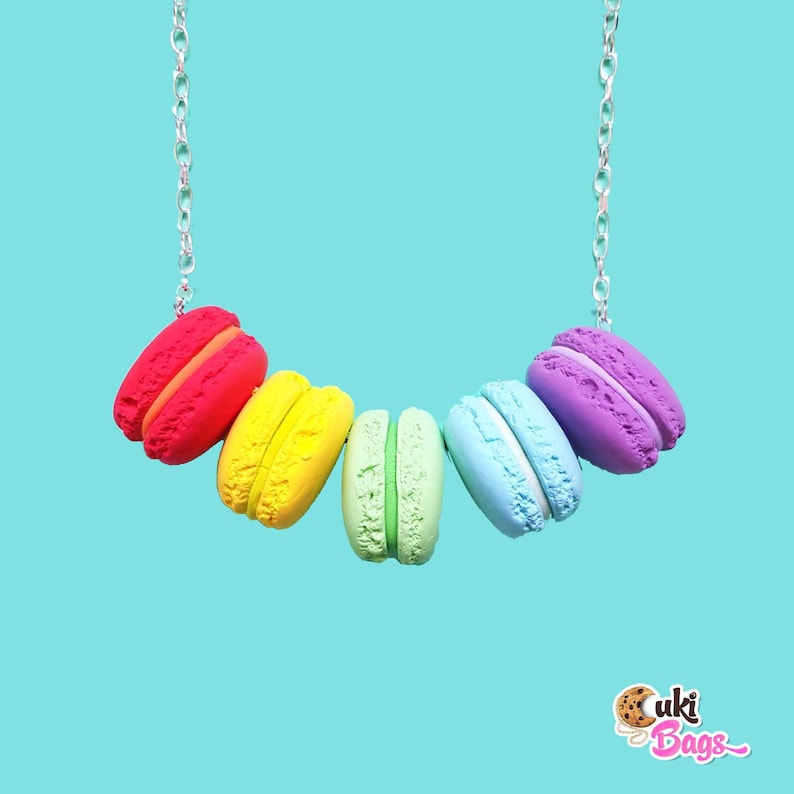 Pode incluir: Um colar de macarons arco-&iacute;ris com uma corrente prateada. Os macarons s&atilde;o vermelho, amarelo, verde, azul e roxo.
