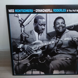 Puede incluir: Foto en blanco y negro de dos hombres tocando música. El hombre de la izquierda está tocando la guitarra y el hombre de la derecha está tocando el saxofón. El texto "WES MONTGOMERY - CANNONBALL ADDERLEY & The Poll Winners" está en la parte superior de la imagen.
