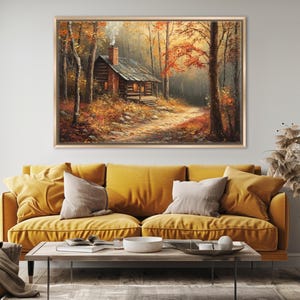 May include: A framed painting depicts a rustic cabin nestled in a forest during autumn. The cabin, with a smoking chimney, is surrounded by trees with vibrant orange and red leaves. A path leads to the cabin, creating a serene, natural scene.