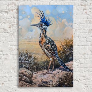 May include: A canvas print of a roadrunner bird. The bird has a blue crest, speckled brown and black feathers, and stands on a rock. The background features a blue sky with clouds and a desert landscape.
