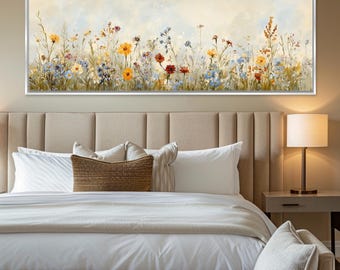 May include: A rectangular framed canvas art piece depicting a field of wildflowers in shades of yellow, red, blue, and purple. The artwork is mounted above a bed with white linens and a beige headboard. A lamp sits on a nightstand.