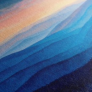 The image is a close-up of a textured fabric with a gradient of blue and orange colors, creating a visually striking pattern.