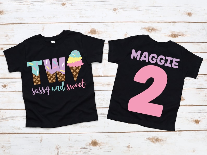 Pu&ograve; includere: Due magliette nere con un design a forma di cono gelato. La parte anteriore di una maglietta dice "TWO sassy and sweet" e la parte posteriore dell'altra maglietta dice "MAGGIE 2".