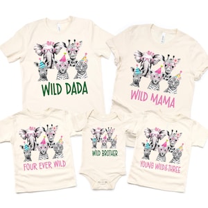 May include: A set of four cream-colored t-shirts with a jungle animal theme. The shirts feature a black and white elephant, zebra, giraffe, and tiger wearing party hats and glasses. The text on the shirts reads "Wild Dada", "Wild Mama", "Four Ever Wild", and "Young Wild & Three".