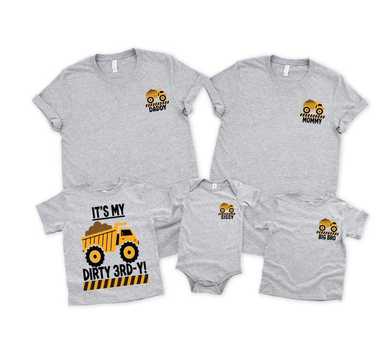 May include: A collection of five heather gray t-shirts and one bodysuit featuring yellow dump truck graphics. The shirts are labeled DADDY, MOMMY, SISSY, and BIG BRO. One shirt features a large dump truck graphic with the text IT'S MY DIRTY 3RD-Y!