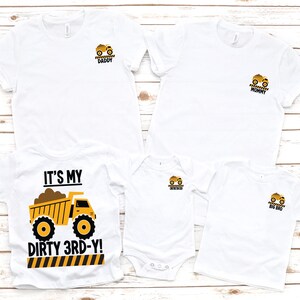 May include: A set of five white t-shirts and one white bodysuit featuring yellow dump truck graphics. One shirt displays the text IT'S MY DIRTY 3RD-Y, while the others feature smaller truck icons with the labels DADDY, MOMMY, BIG BRO, and a blank one.