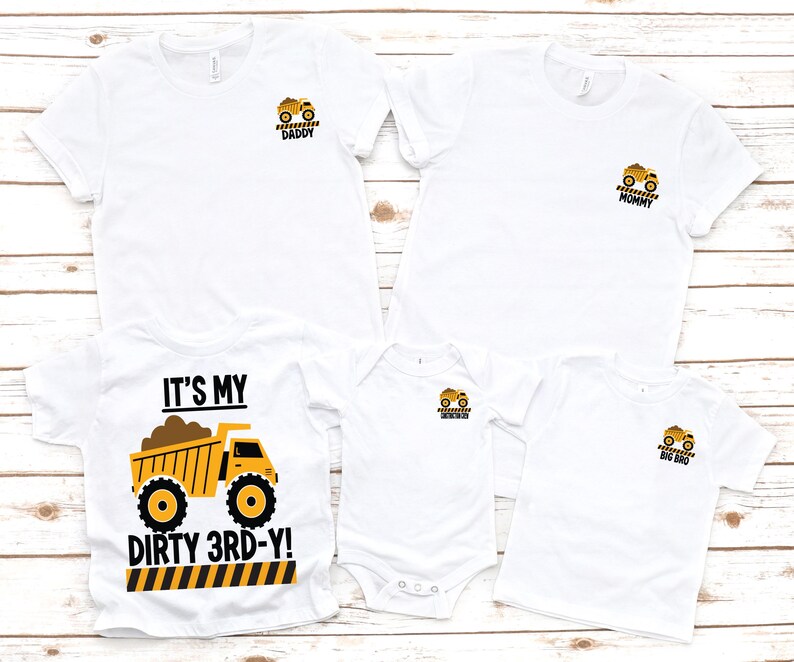 May include: A set of five white t-shirts and one white bodysuit featuring yellow dump truck graphics. One shirt displays the text IT'S MY DIRTY 3RD-Y, while the others feature smaller truck icons with the labels DADDY, MOMMY, BIG BRO, and a blank one.