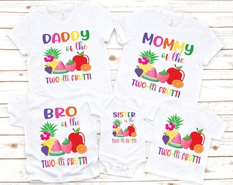 May include: A set of four white t-shirts with colorful fruit graphics and text that reads "Daddy of the Two-lit Frutti", "Mommy of the Two-lit Frutti", "Bro of the Two-lit Frutti", and "Sister of the Two-lit Frutti".
