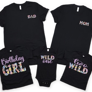 May include: Black t-shirts with floral text designs. The shirts include "DAD" and "MOM" on the front, and "Birthday GIRL", "Wild One", and "Two Wild" on others. A family matching apparel set.