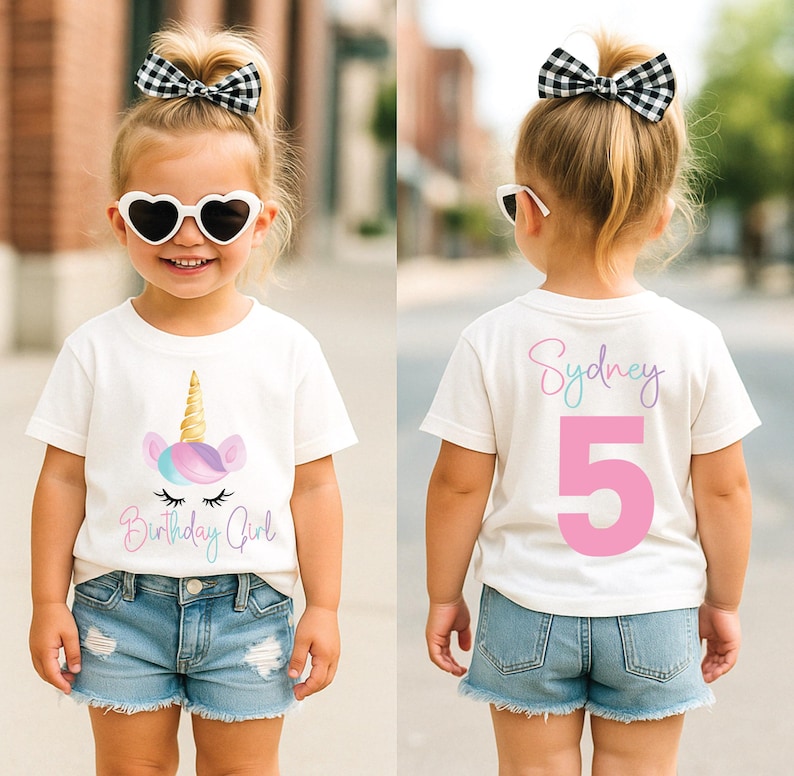 May include: A white t-shirt with a unicorn graphic and the text "Birthday Girl". The back of the shirt has the name "Sydney" and the number "5". The child is wearing denim shorts, heart-shaped sunglasses, and a black and white bow.