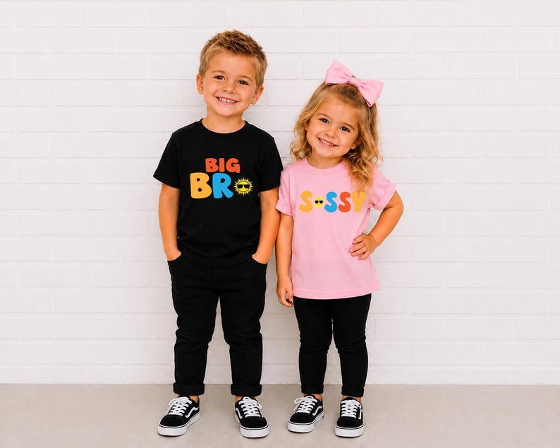 May include: A black t-shirt with the text BIG BRO in orange and blue with a yellow sun icon wearing sunglasses, and a light pink t-shirt with the text S-SSY in yellow, pink, and orange with a yellow smiley face icon wearing sunglasses.