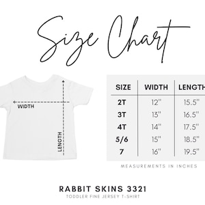 May include: A white toddler fine jersey t-shirt, Rabbit Skins 3321, with a size chart displaying width and length measurements in inches for sizes 2T through 7. The chart lists specific dimensions for each size, ranging from 12 to 16 inches in width and 15.5 to 19.5 inches in length.