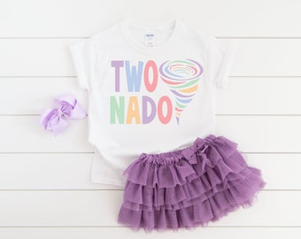 以下が含まれることがあります： 「TWO NADO」の文字とカラフルな竜巻のグラフィックがプリントされた白いTシャツ。紫色のチュチュスカートと、お揃いのリボンも画像にあります。この衣装は、子供の2歳の誕生日のためにデザインされています。