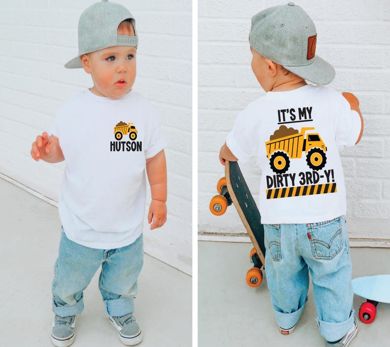 May include: A white short-sleeve t-shirt featuring a yellow dump truck graphic. The front displays the truck with the name Hutson. The back features the same truck with the text IT'S MY DIRTY 3RD-Y! above a yellow and black caution stripe pattern.