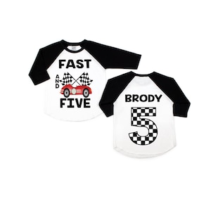 May include: A white and black baseball style shirt with the text "Fast and Five" and a red race car with checkered flags. The back of the shirt has the name "Brody" and the number "5" in a checkered pattern.