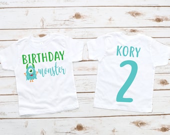 May include: Two white t-shirts with a blue monster graphic and the text "Birthday monster" on one shirt and the name "Kory" and the number "2" on the other shirt.