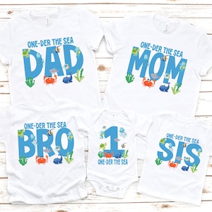 May include: Set of four white t-shirts with blue and green sea creature graphics. The shirts say "One-der the Sea" and "Dad", "Mom", "Bro", and "Sis".