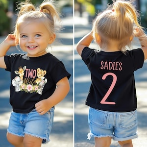 May include: A black t-shirt with a pink "TWO WILD" graphic featuring a lion, giraffe, and elephant. The back of the shirt has a pink "SADIES 2" graphic.
